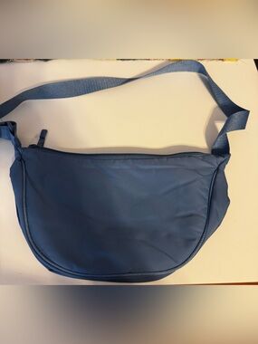 Blue NWOT  Crossbody Bag featuring a smooth, curved silhouette and an adjustable